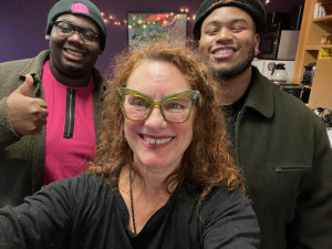 Word Is Bond: THE BLACK STARS three people smile in the lobby of the community radio station.